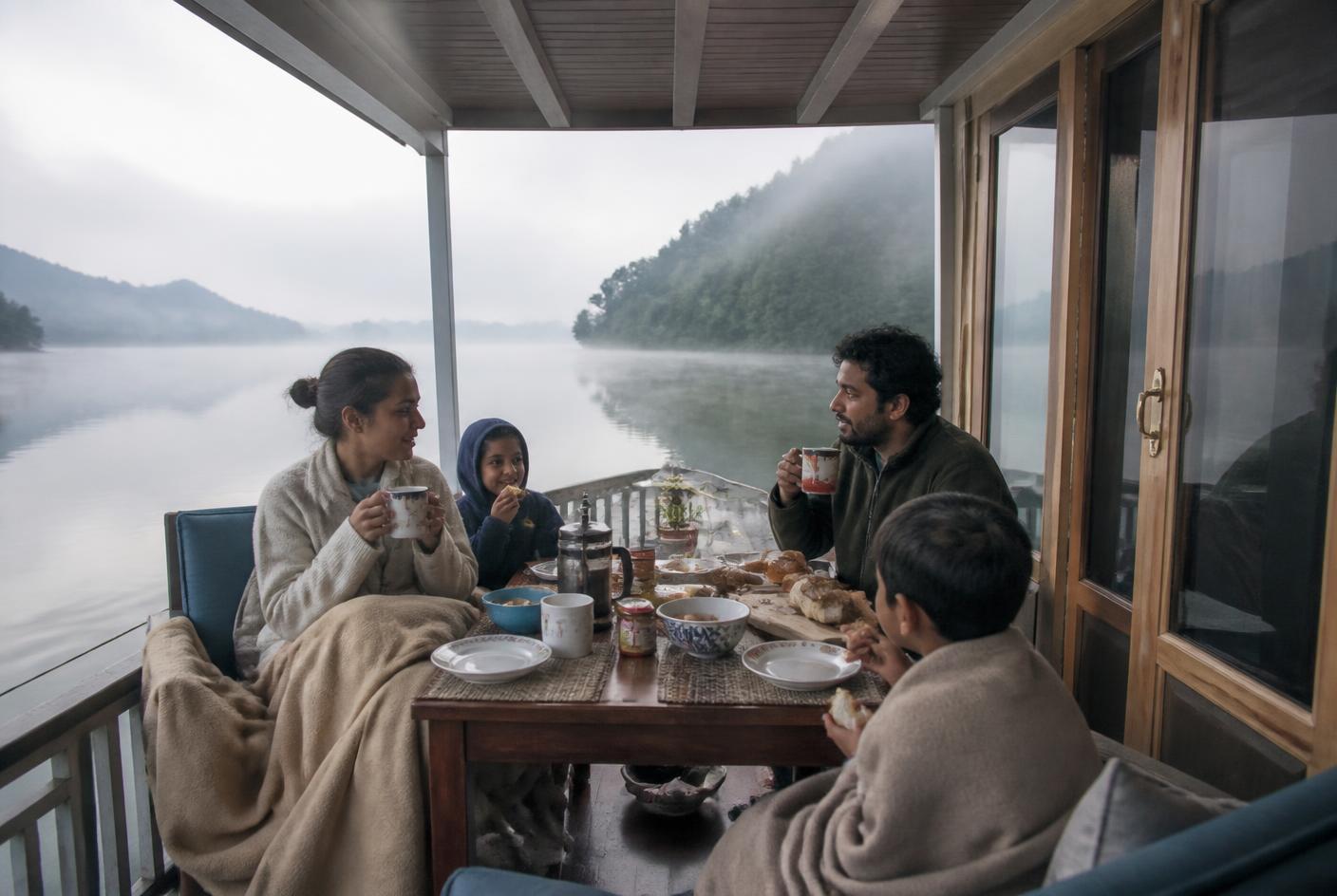Familie frühstückt am Morgen auf dem Achterdeck eines Hausboots im Nebel