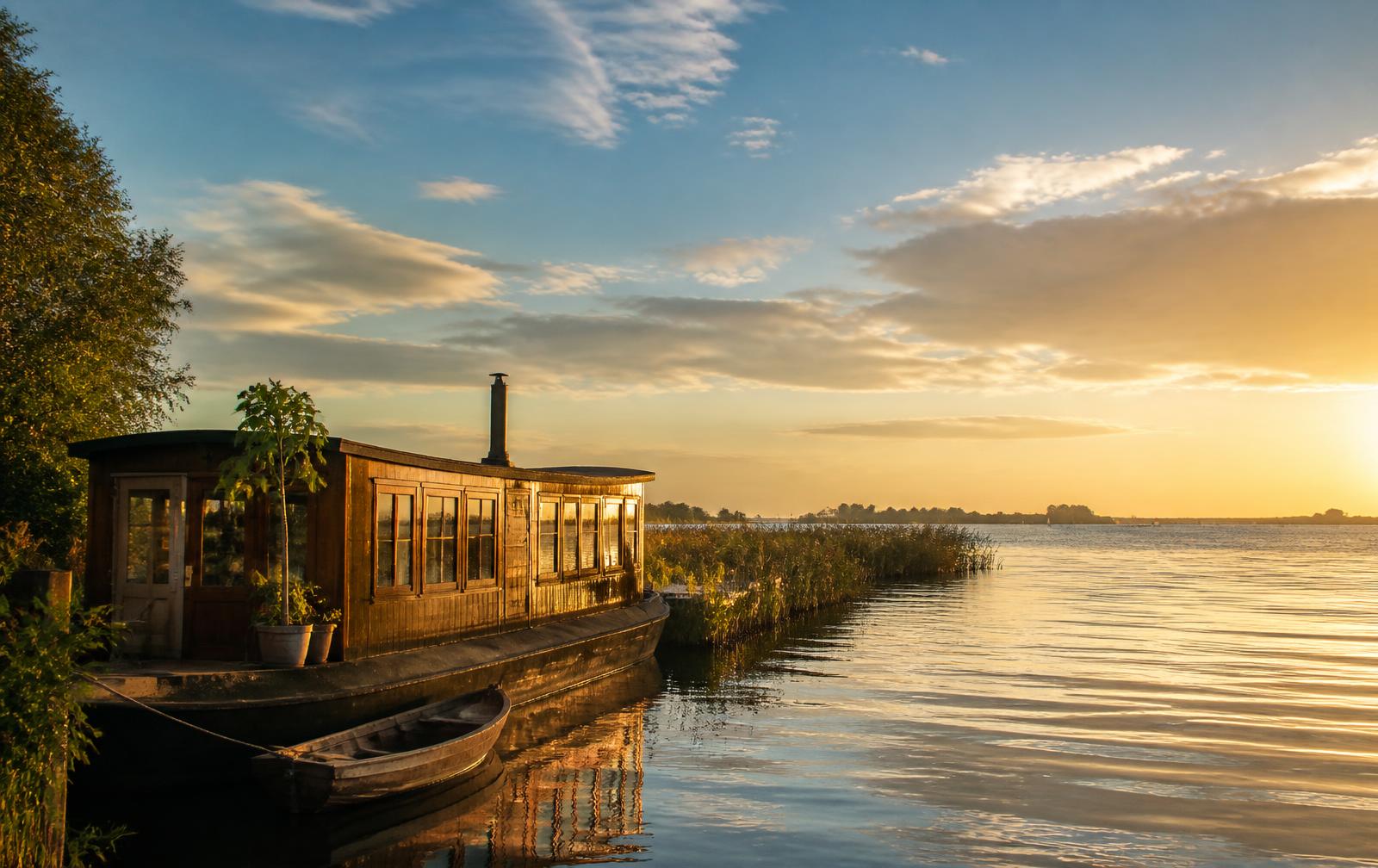 Hölzernes Hausboot im Abendlicht am Schilfrand eines friesischen Sees